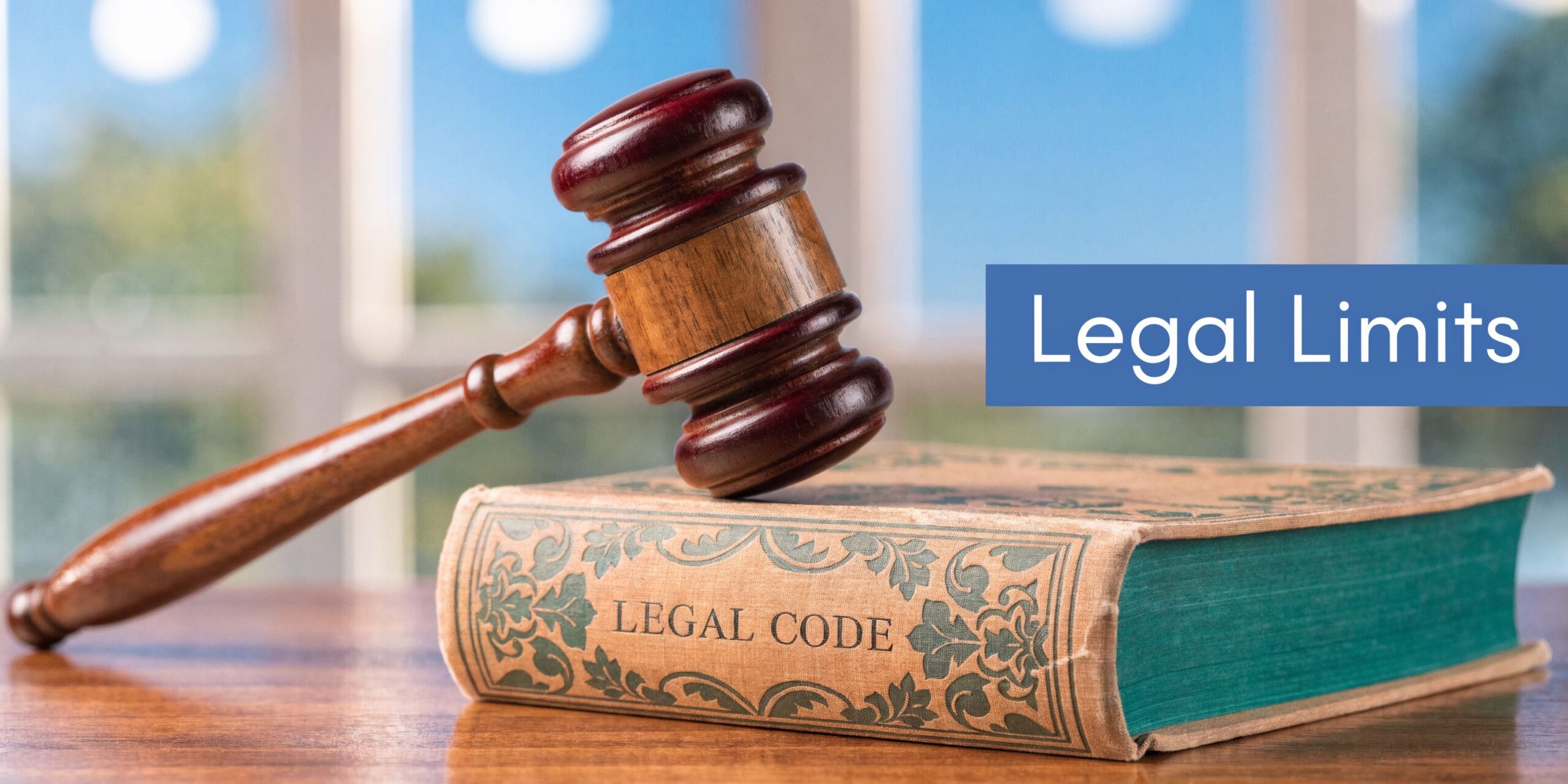 A wooden gavel resting on top of an antique book titled Legal Code on a desk.