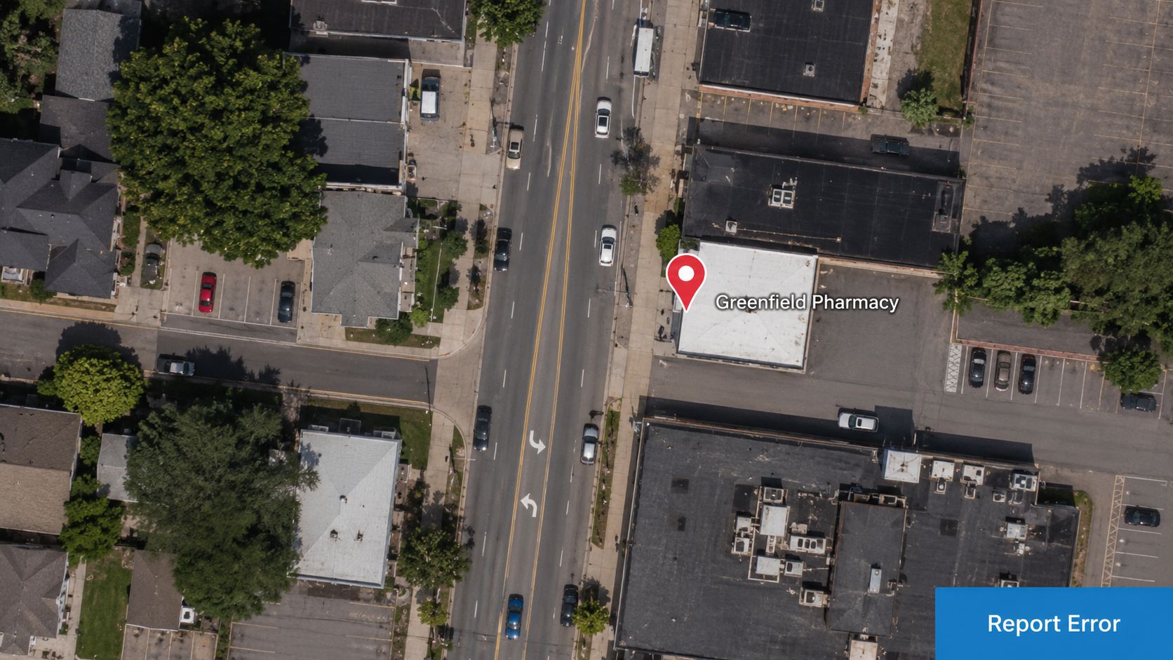 An aerial view showing a street intersection with a red location pin marking Greenfield Pharmacy.